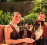 Photo of two people sitting outside, one holding a guitar, with Otis the dog between them