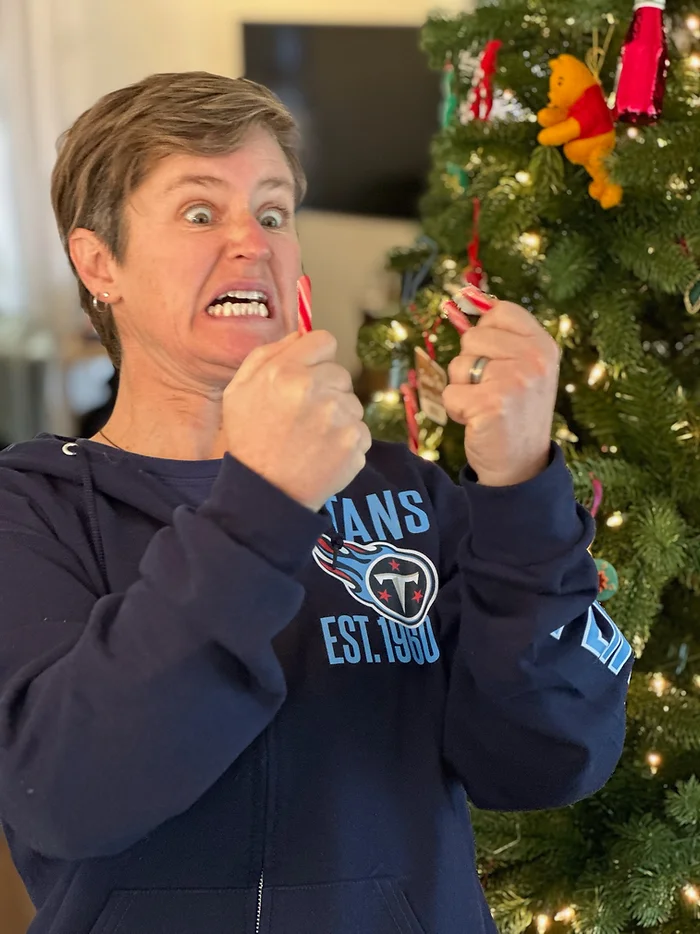 Photo of Molly Booker holding a broken candy cane in front of a Christmas tree