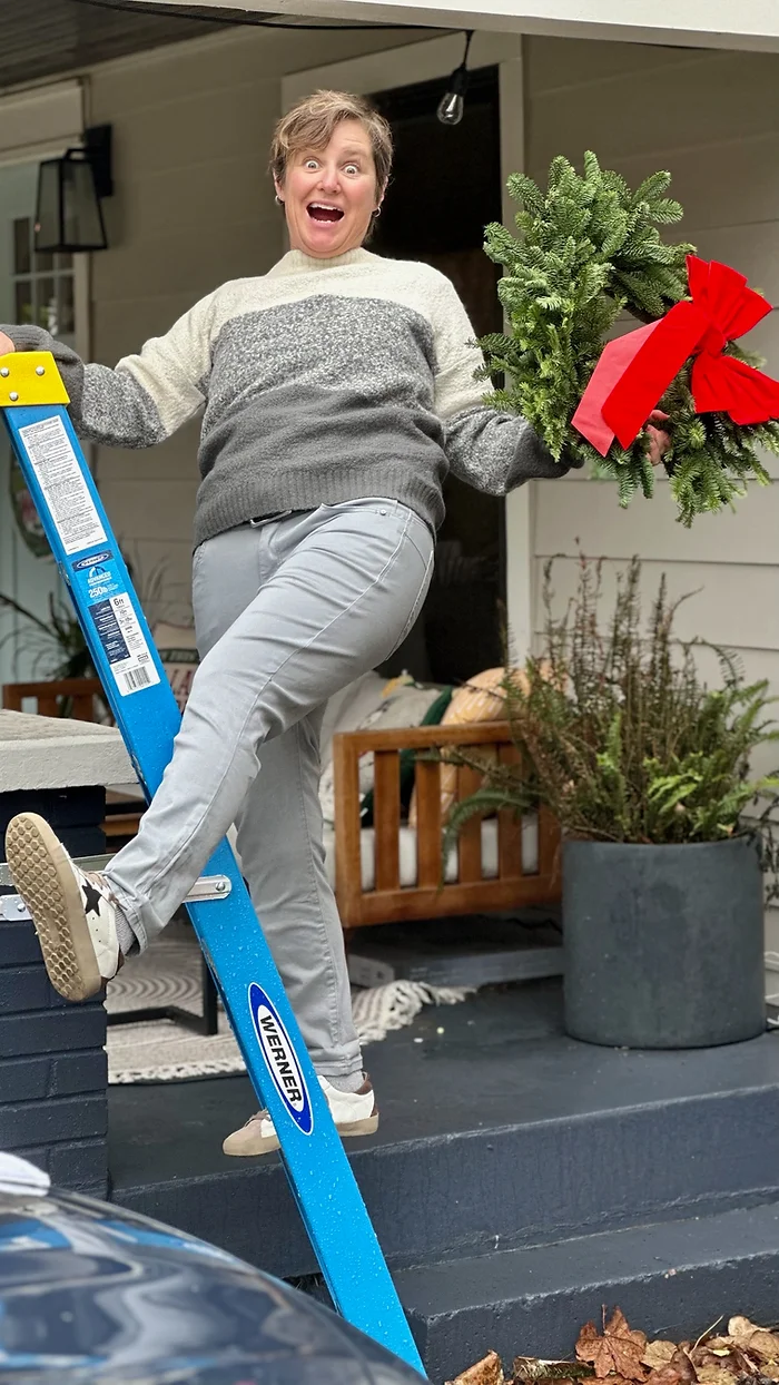 Photo of Molly Booker on a ladder with a wreath