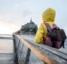 Photo of a person in a yellow jacket wearing a backpack, staring out across a body of water