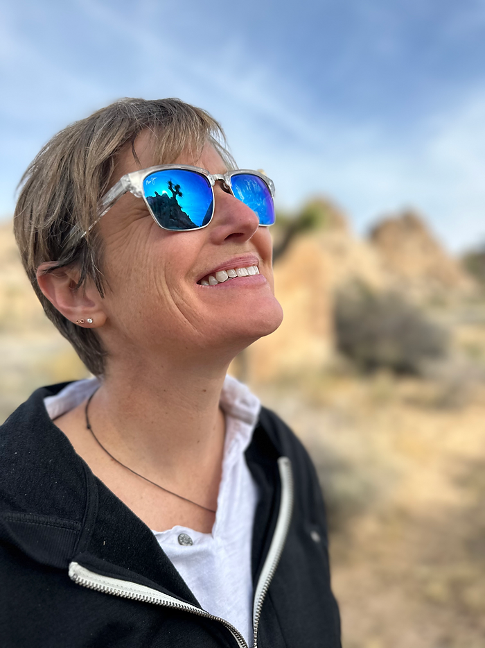 Photo of Molly Booker wearing sunglasses, looking up and smiling